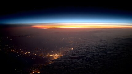 Fototapeta premium Aerial view shows horizon with orange glow above dark clouds and city lights.