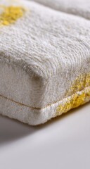 Close-up of a textured, off-white rectangular object with yellow stains