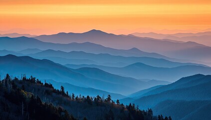 Obraz premium Sunrise hues paint mountain ranges. Layers of blue-toned peaks