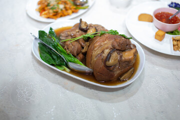 Braised pork leg served on a white plate with kale