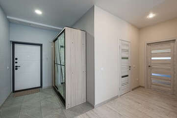 modern hallway with gray tile flooring, a sliding door wardrobe, and two interior doors