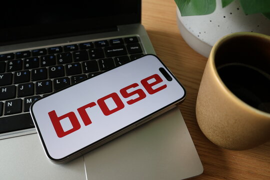 Kiel, SH, Germany, 08-07-2025: Close-up of a smartphone displaying the brose logo on a laptop keyboard beside a coffee cup and a green plant