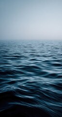 Obraz premium Calm, dark ocean surface, subtle waves. A vast, misty horizon