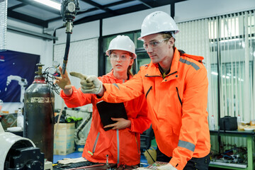 technicians analyzing robotic equipment interface and discussing programming process during team based industrial automation training session in modern smart factory