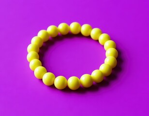 Obraz premium A lemon-yellow bracelet made of round beads on a solid purple surface.