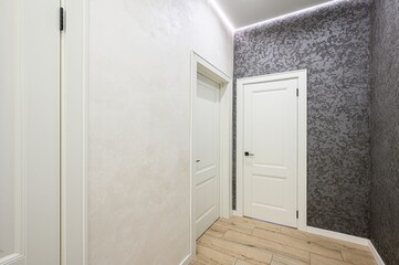 interior shot of a hallway with white doors and textured walls. Light wood flooring adds warmth to the modern space