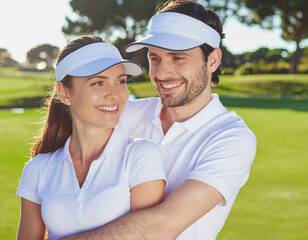 A happy couple embracing on a golf course in the sunshine