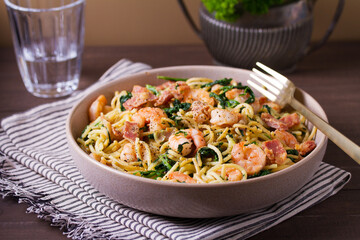Seafood pasta with spinach and bacon. Spaghetti with shrimps