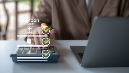 Businessman calculating carbon credit with virtual checklist interface. Concepts of carbon emission reduction, ESG reporting, green finance, environmental sustainability, and corporate responsibility.