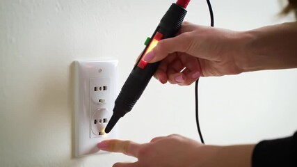 footage hand testing electrical outlet with voltage tester