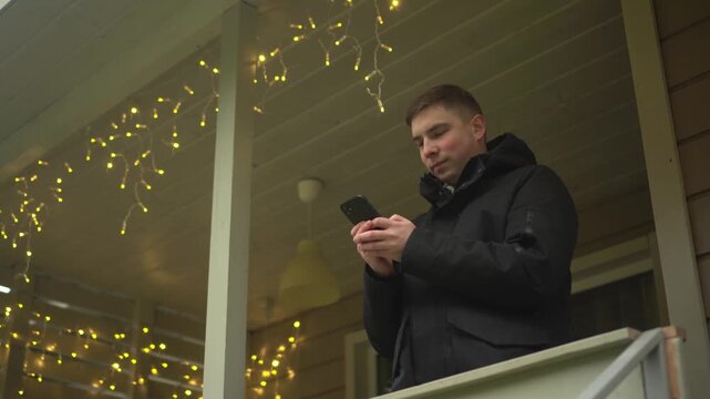a man relaxing on his porch is using his smartphon