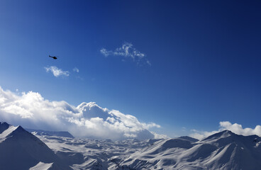 Helicopter above snowy plateau and sunny sky