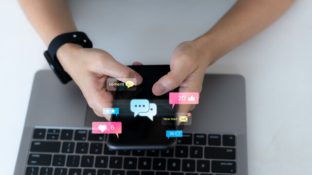 Hands holding a smartphone with floating social media icons such as like, comment, email, and rating notifications. Concept of online interaction, social engagement, and digital communication. - Powered by Adobe