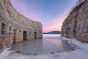 Stone fort on frozen lake, pink sunrise