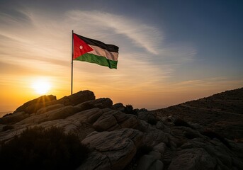 Symbol of Jordan: National flag atop rocky mountain at breathtaking sunset