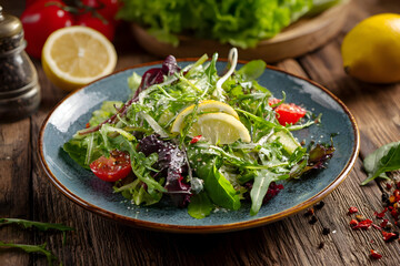 Fresh Arugula Salad with Lemon and Tomato on a Rustic Blue Ceramic Plate.