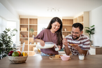 Happy couple enjoying breakfast with waffles and milk at home