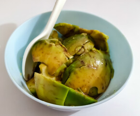A simple light blue bowl filled with a homemade green avocado fruit snack ready to eat
