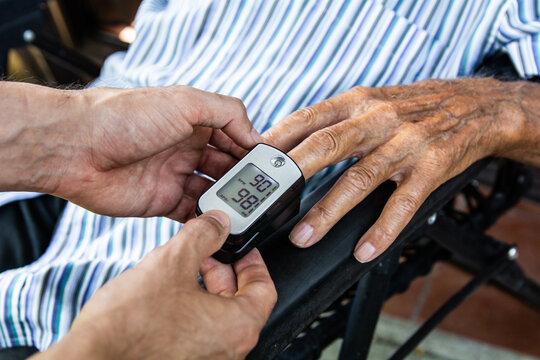 Senior person getting oxygen and heart rate monitored with pulse oximeter at home, elderly care and health checkup concept - Powered by Adobe