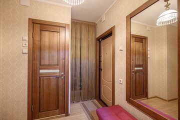 cozy foyer with wooden doors, a mirror, and a beaded curtain. Warm lighting and patterned wallpaper add to the inviting ambiance