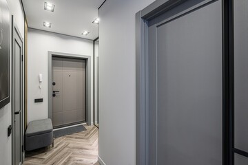Modern entryway with grey doors, herringbone floor, and recessed lighting. Bench seating and a doormat add functionality
