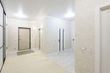 well-lit hallway with neutral tones, featuring doors, a sliding door closet, and a beige carpet