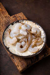  Raw shrimps in a plate on the dark background vertical photo