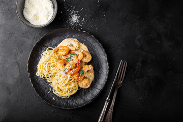 Pasta with shrimps in creamy sauce in a plate on black background top view copy space for text