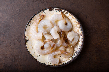  Raw shrimps in a plate on the dark background top view