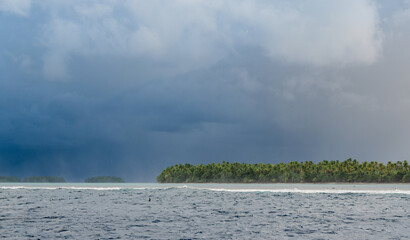 Storm approaching an Island while waves are crashing over the reef barrier