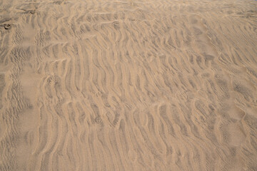 The image is of a sandy beach with a tan color. The sand is very fine and the beach appears to be empty