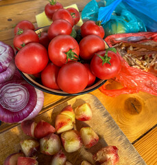 Fresh colorful vegetables on a kitchen table, including tomatoes, onion, and bell peppers.
