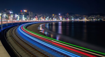 Night coastal train tracks with colorful light trails