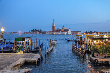 Obraz premium Gondolas and boats at dusk on the island of San Giorgio Maggiore in Venice, Italy.
