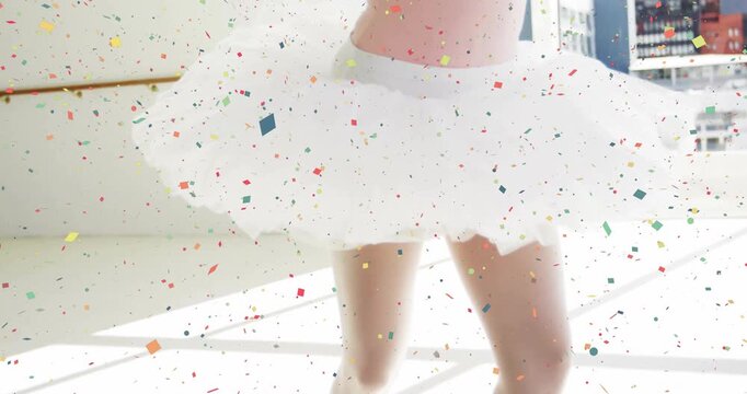 Female ballet dancer raising onto pointe in studio, executing arabesque for training amid confetti