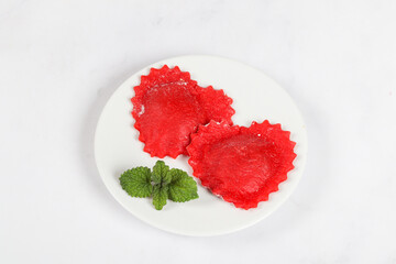 Two Red heart-shaped ravioli. On a ceramic plate. White background. Top view	