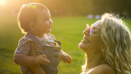 Smiling grandmother holding baby girl outdoors in the park