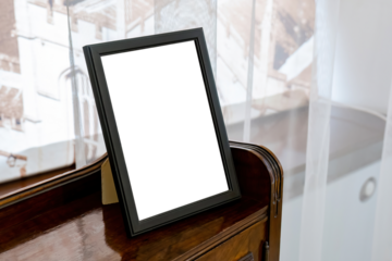 Simple black tabletop picture frame with a stand placed on a wooden shelf at home, blank white space inside mockup template for person portrait photo, simple home interior decor element, no people