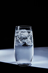 Refreshing glass of cold water with ice cubes and condensation on a dark background, showcasing clear liquid and icy freshness, perfect for hydration concepts.
