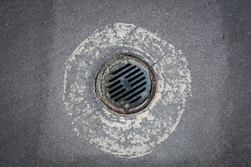 Drain cover on grey asphalt surface