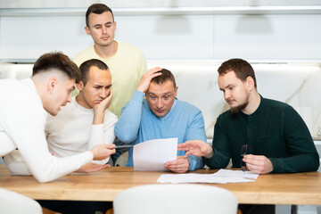 Brainstorming - male friends trying to solve financial problems by consulting at the table in the home kitchen