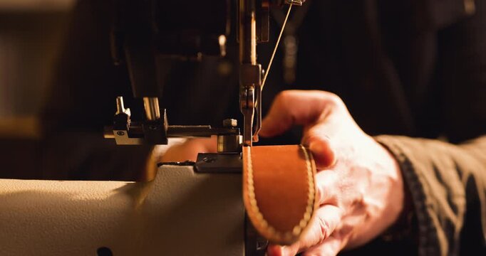 Shoemaker crafting leather belt with sewing machine in workshop