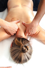 Naklejka premium Close up of therapist hands applying firm pressure along the client is upper back muscles on a white massage table, focusing on muscle relaxation, tactile care, therapeutic spa treatment indoors 