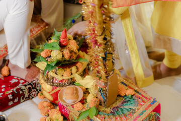 Close-up shot of a Kalash, a sacred pot used in Hindu rituals, adorned with flowers and auspicious items during a wedding ceremony, signifying prosperity and blessings.