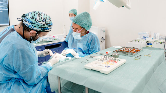 Dental professionals performing implant surgery