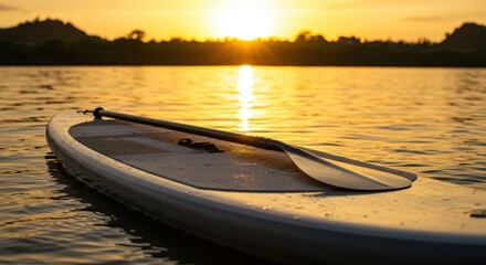 Paddleboard resting on calm water at sunset near serene landscape