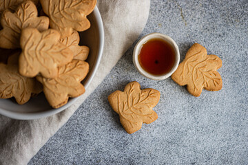 Maple leaf cookies with syrup on gray background