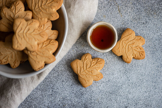 Maple leaf cookies with syrup on gray background
