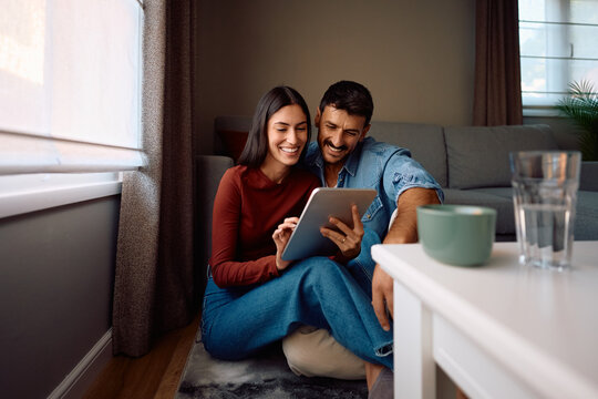 Happy couple using digital tablet while relaxing at home.