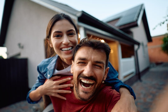 Happy new homeowners having fun while taking selfie in backyard and looking at camera.